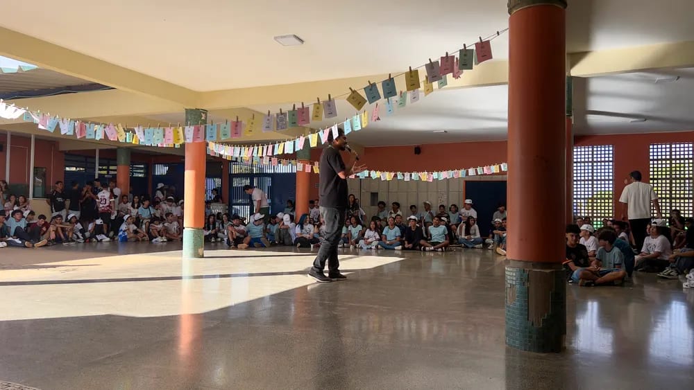 Quadra coberta da escola durante a apresentação, com o público sentado ao fundo