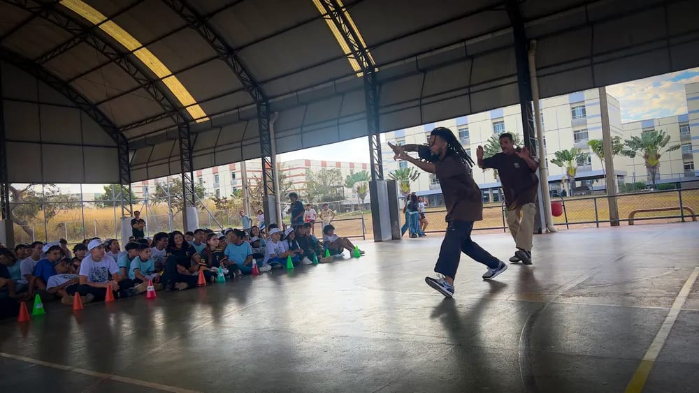 Vista geral da quadra durante a apresentação, com o público acompanhando sentado
